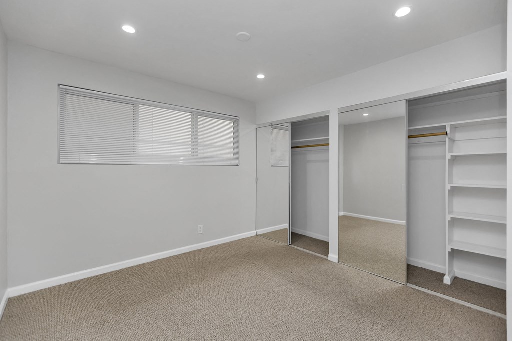 a bedroom with a closet and mirrored closet doors