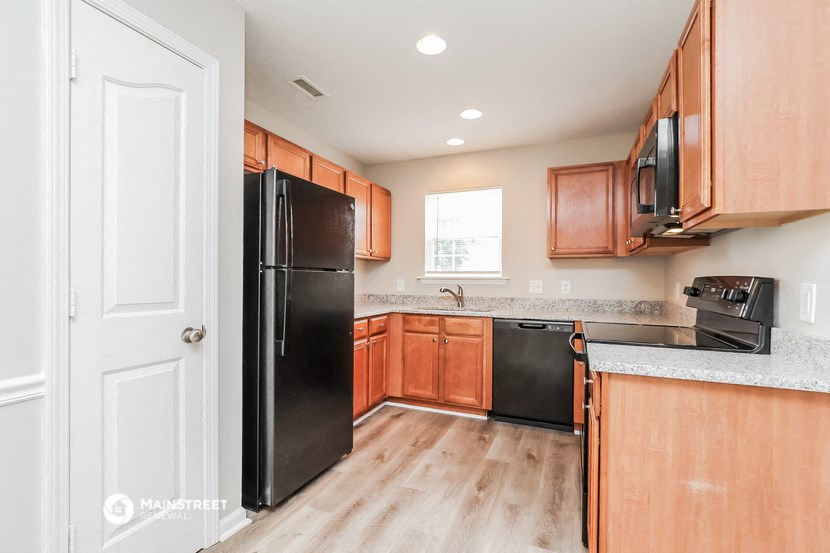 a kitchen with wooden cabinets and a black refrigerator