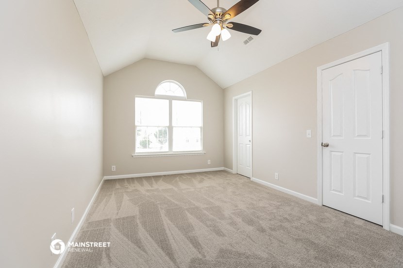 the master bedroom is spacious and clean with a ceiling fan