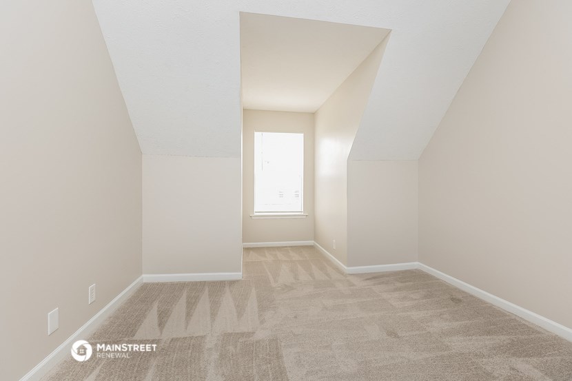 an empty room with a window and carpeting