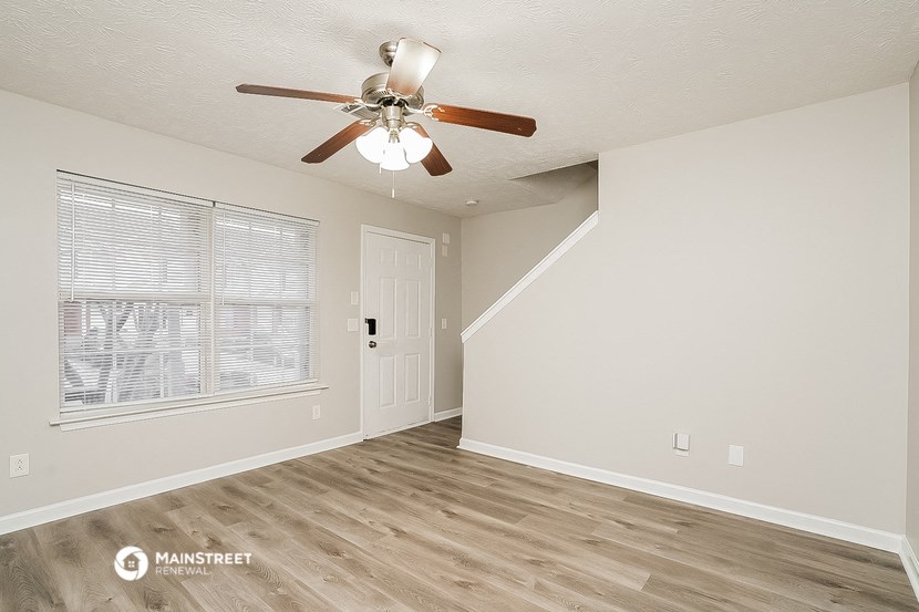 the spacious living room with ceiling fan and window