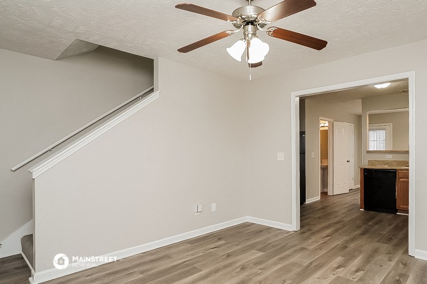 an empty living room with a ceiling fan