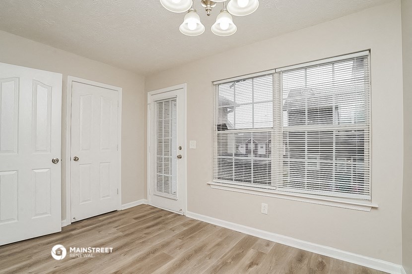 the living room of an apartment with a large window and a door to the closet