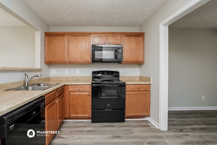 an empty kitchen with wooden cabinets and a black stove and refrigerator