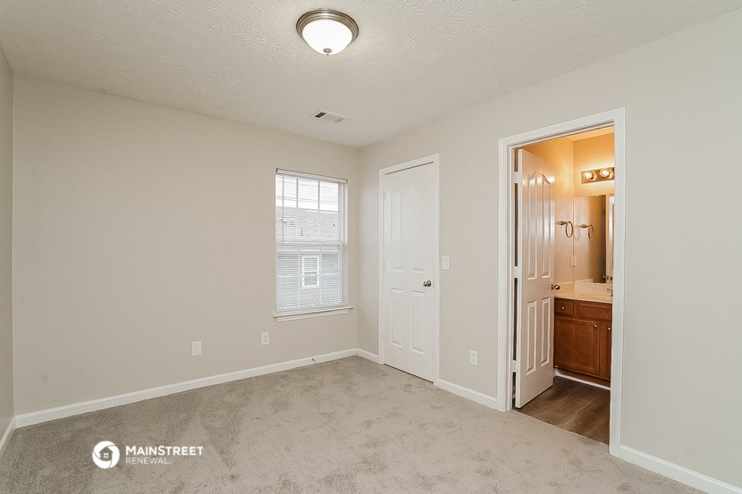 a bedroom with a door to a bathroom and a closet