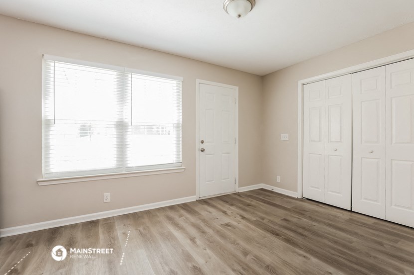 the spacious living room with two doors and a window