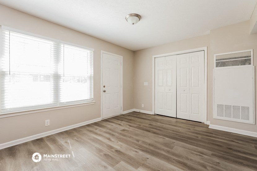 the living room of an apartment with wood flooring and a white door