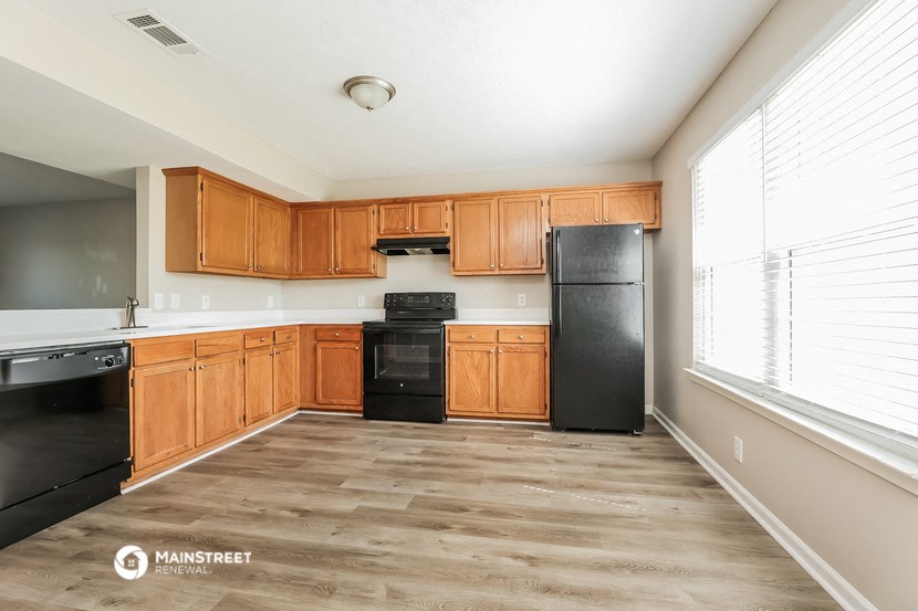 an empty kitchen with wooden cabinets and black appliances