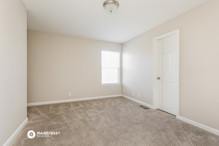 the spacious living room with carpet and a door to the bedroom