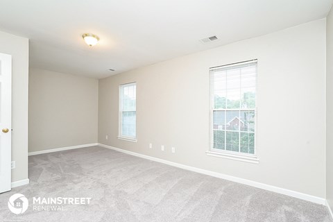 the living room of a new home with white carpet and two windows