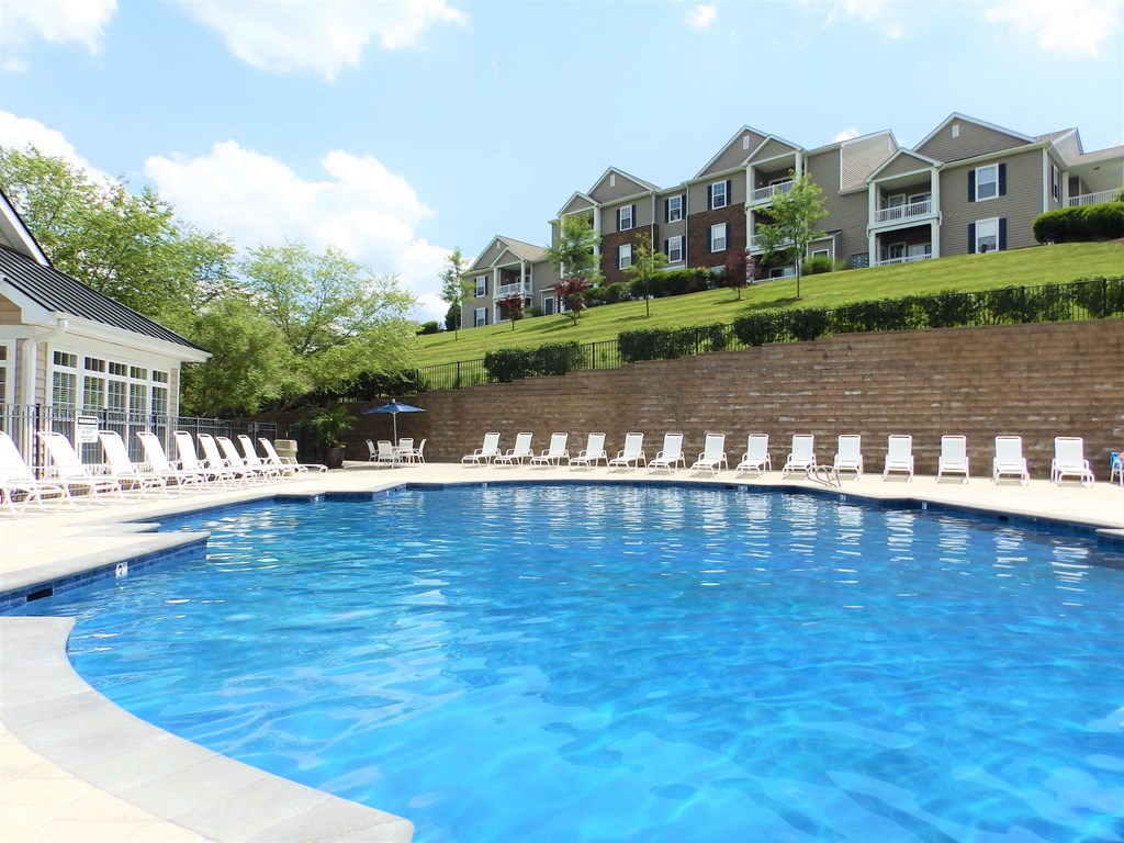 a swimming pool with white chairs and a building in the background