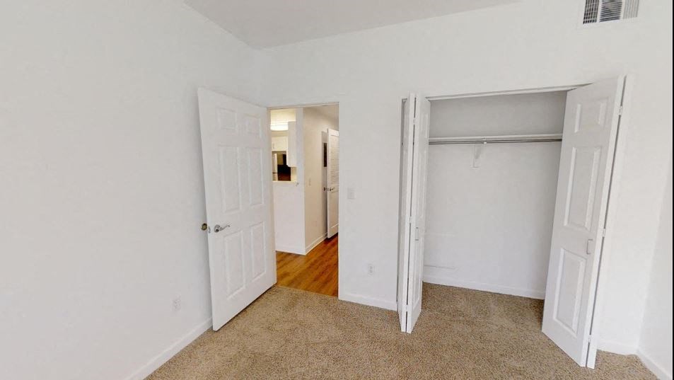 an empty bedroom with a closet and an open door