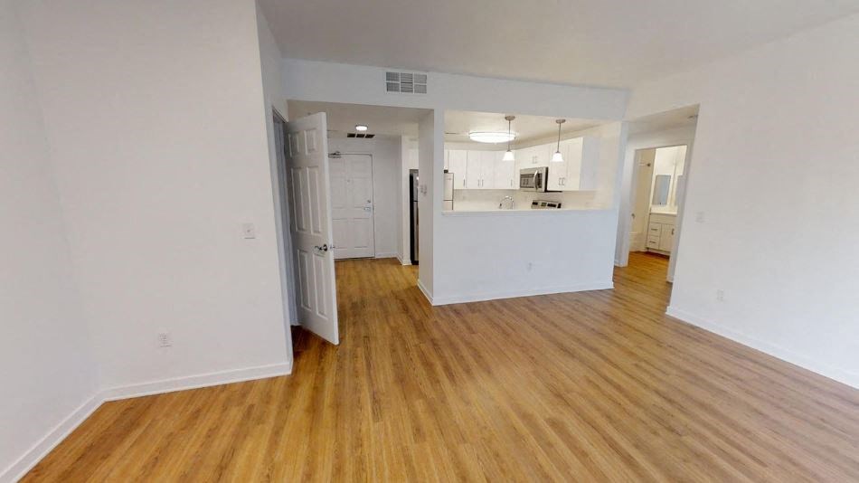 an empty living room and kitchen with wood floors