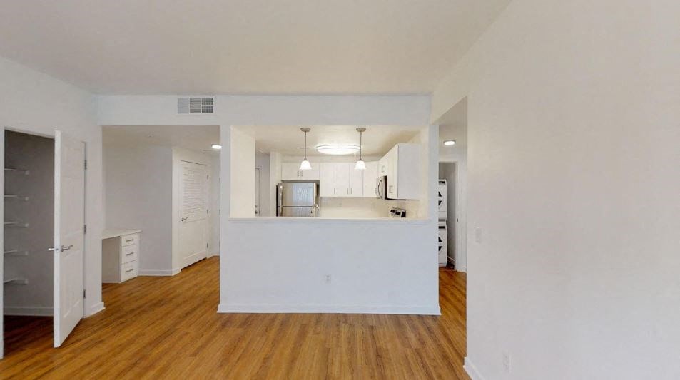 an empty living room and kitchen with a wood floor