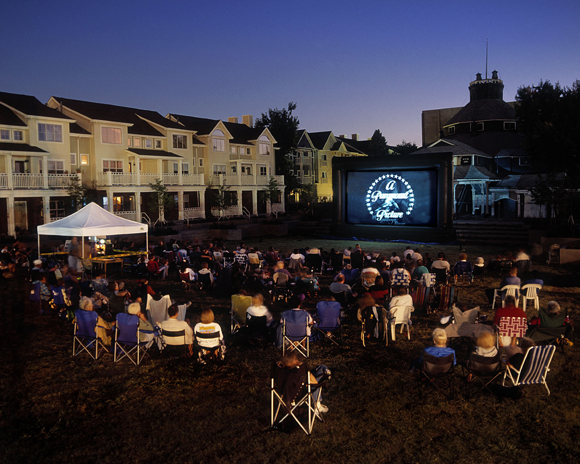 a crowd of people watching a movie on a projector screen at night