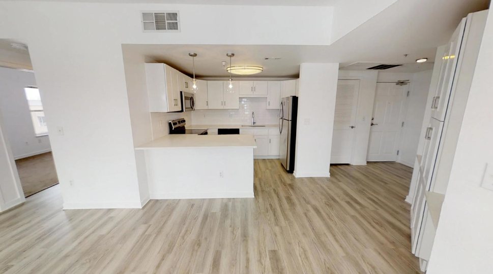 an empty living room and kitchen with white walls and wood floors