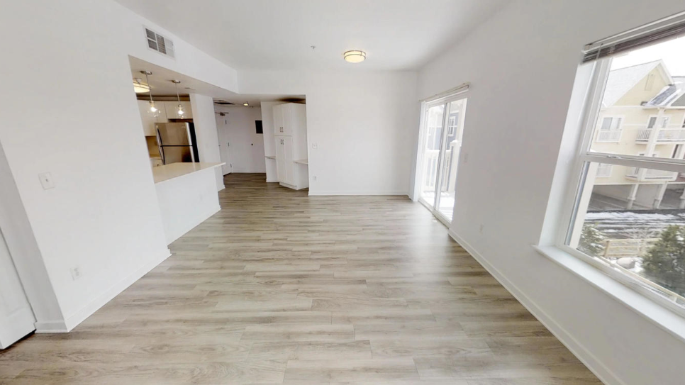a renovated living room and kitchen with white walls and wood floors