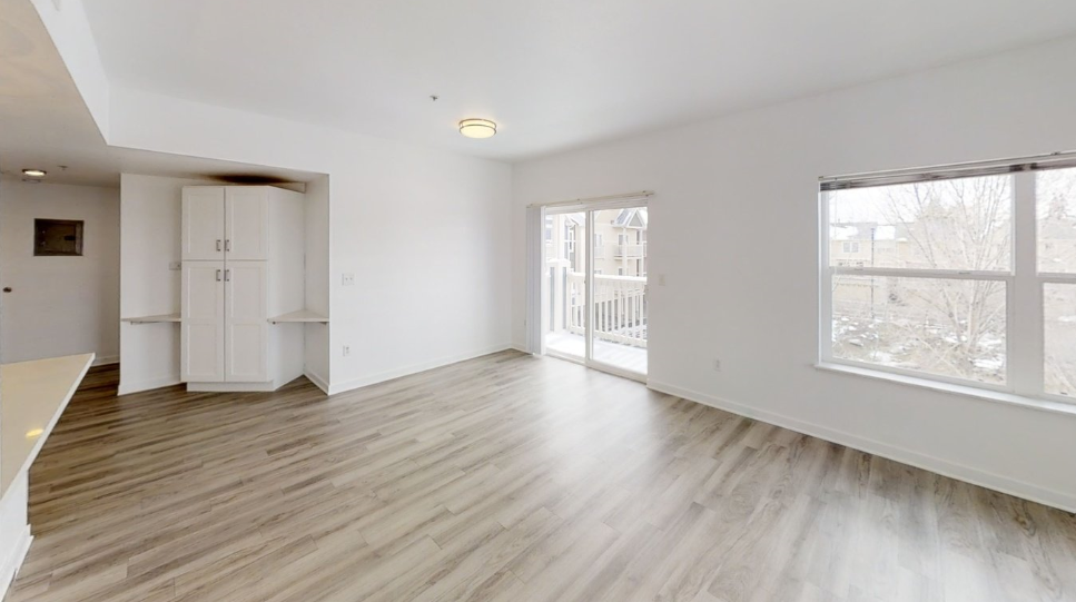 an empty living room with wood floors and a large window