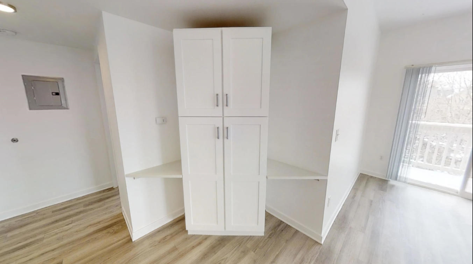 an empty room with white cabinets and a window