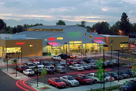 a parking lot full of cars in front of a shopping center