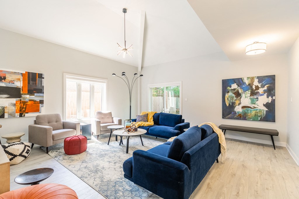 a living room with blue couches and chairs and a rug