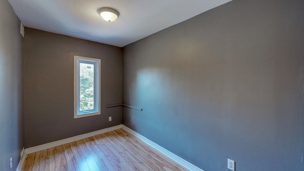 an empty room with gray walls and a window