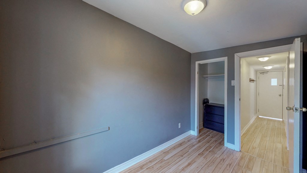 a bedroom with grey walls and a door to a closet and a hallway with wood