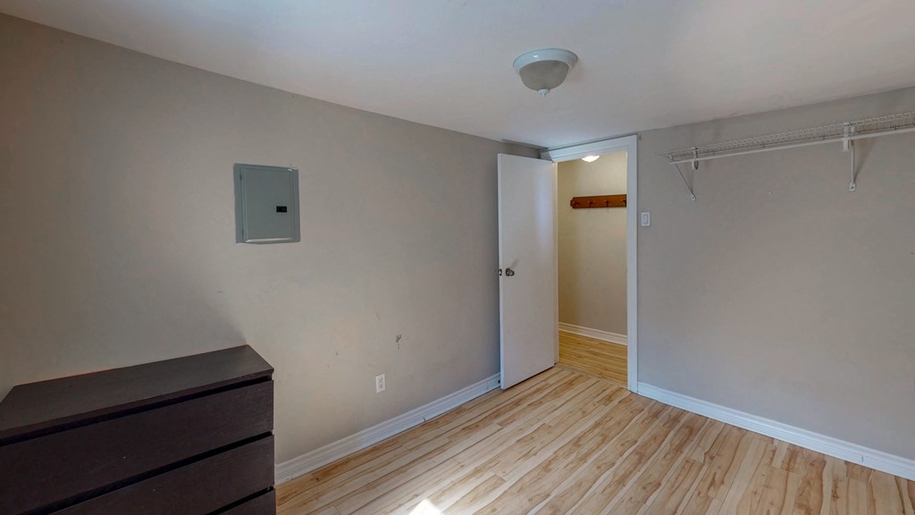 a room with a dresser and a door into a hallway with wood flooring