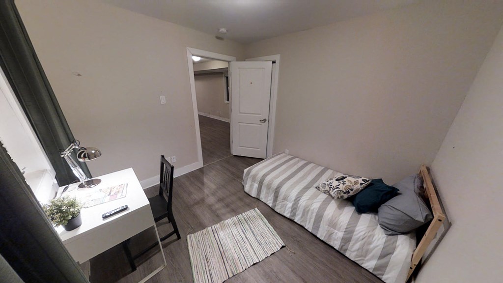 a bedroom with a bed and a desk in a room