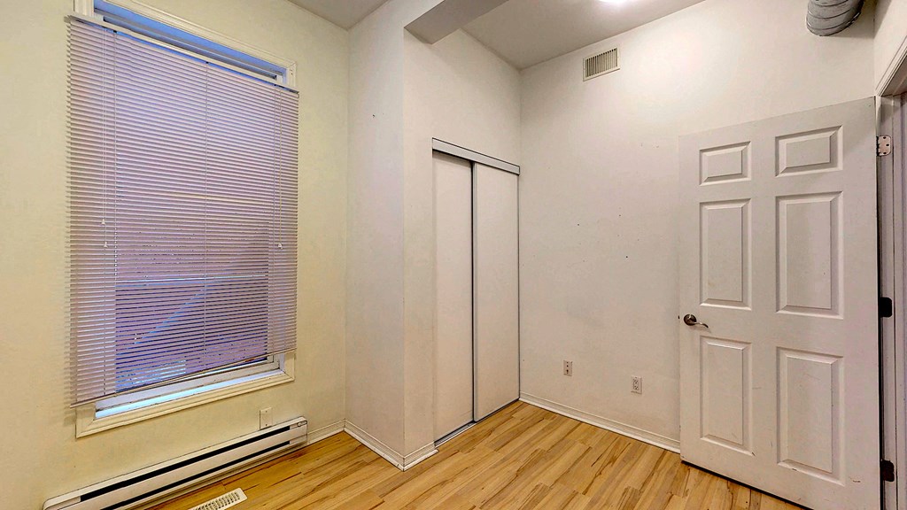 a bedroom with a window and a door and wood floors