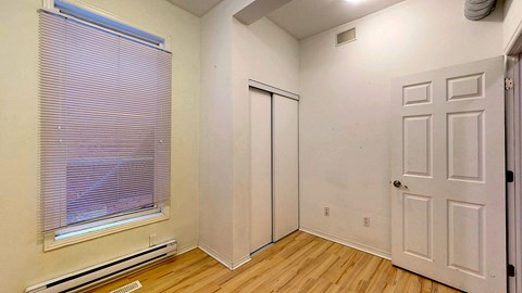 a bedroom with a window and a door and wood floors
