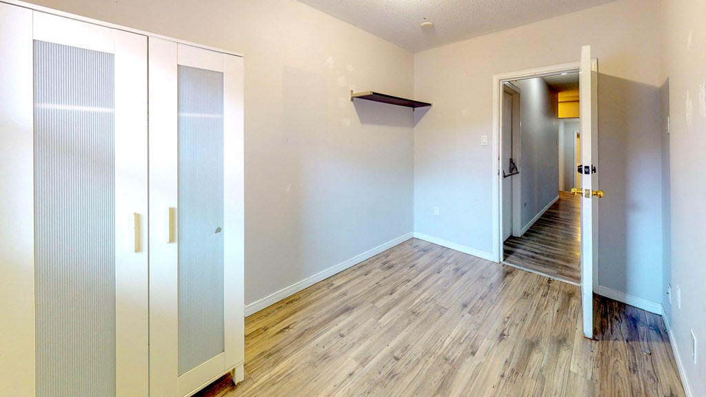 an empty room with wood flooring and white walls and doors