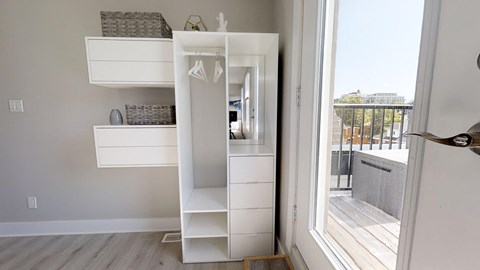 a small white closet in a room with a door to a balcony