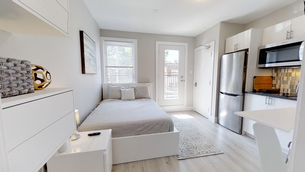 a bedroom with a bed and a refrigerator