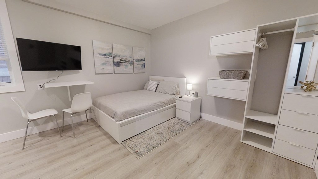 a bedroom with a bed and a desk and a television