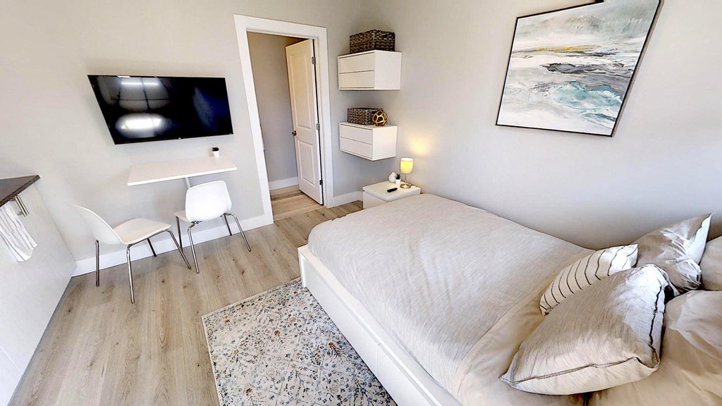 a bedroom with a bed and a desk and a television