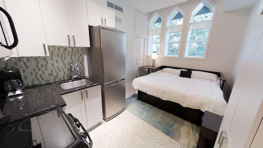 a small bedroom with a bed and a refrigerator