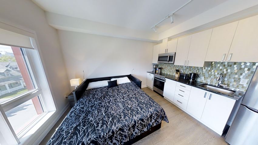 a bedroom with a bed and a kitchen