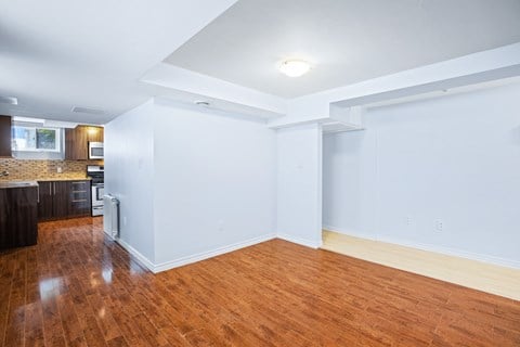 an empty living room and kitchen with wood floors and white walls