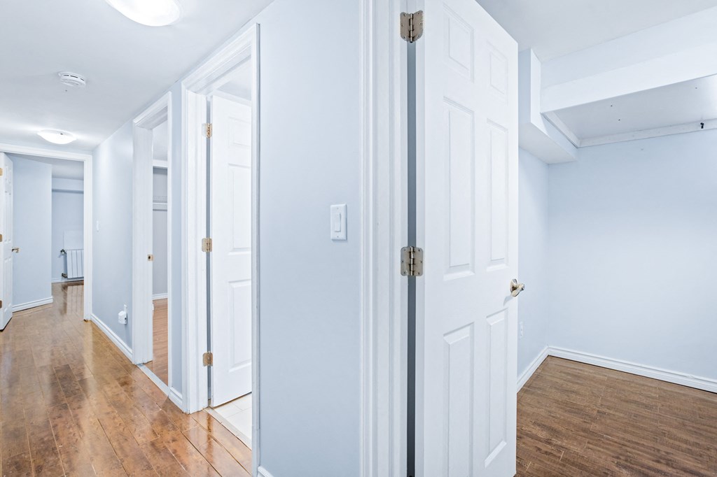 a hallway with white doors and a hard wood floor