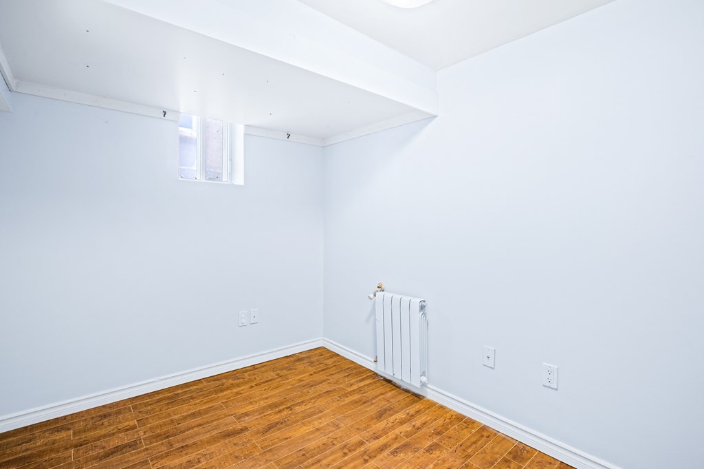 a room with white walls and wood floors and a white radiator