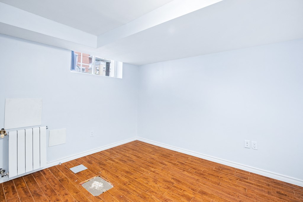 an empty room with a wood floor and white walls