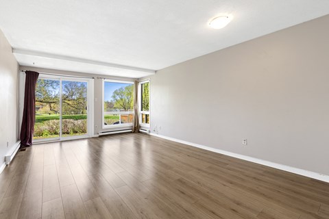 an empty living room with wood flooring and sliding glass doors