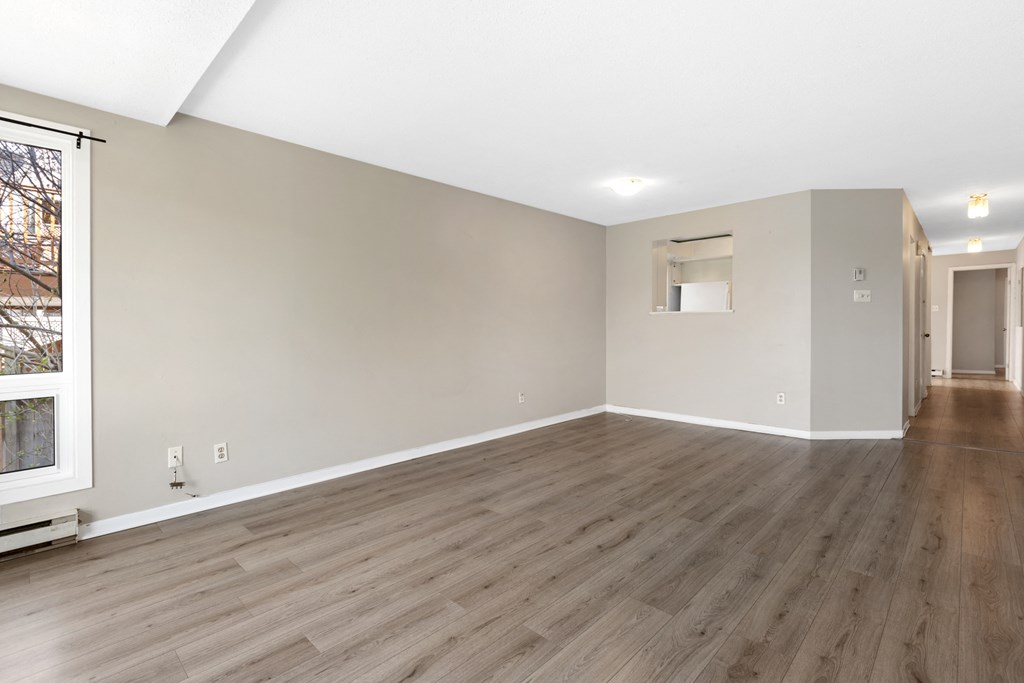 the living room and dining room of an empty house with wood flooring