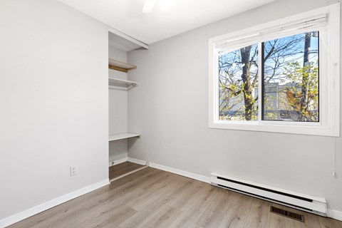 a room with white walls and a large window and wooden floors