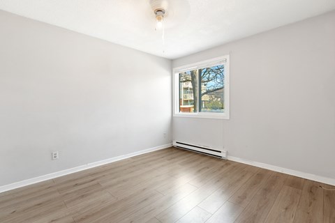 an empty living room with white walls and a window