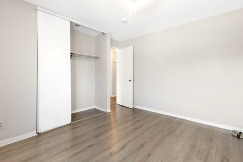 an empty room with white walls and wood floors and a closet