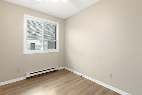a bedroom with wood flooring and a window
