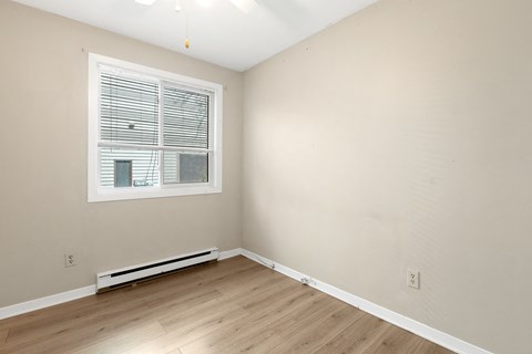 a bedroom with white walls and a window and wooden floors