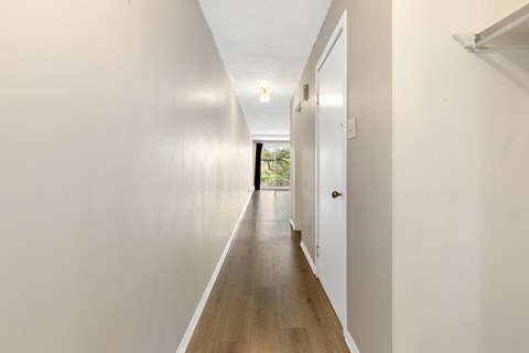a long white hallway with white walls and wood floors